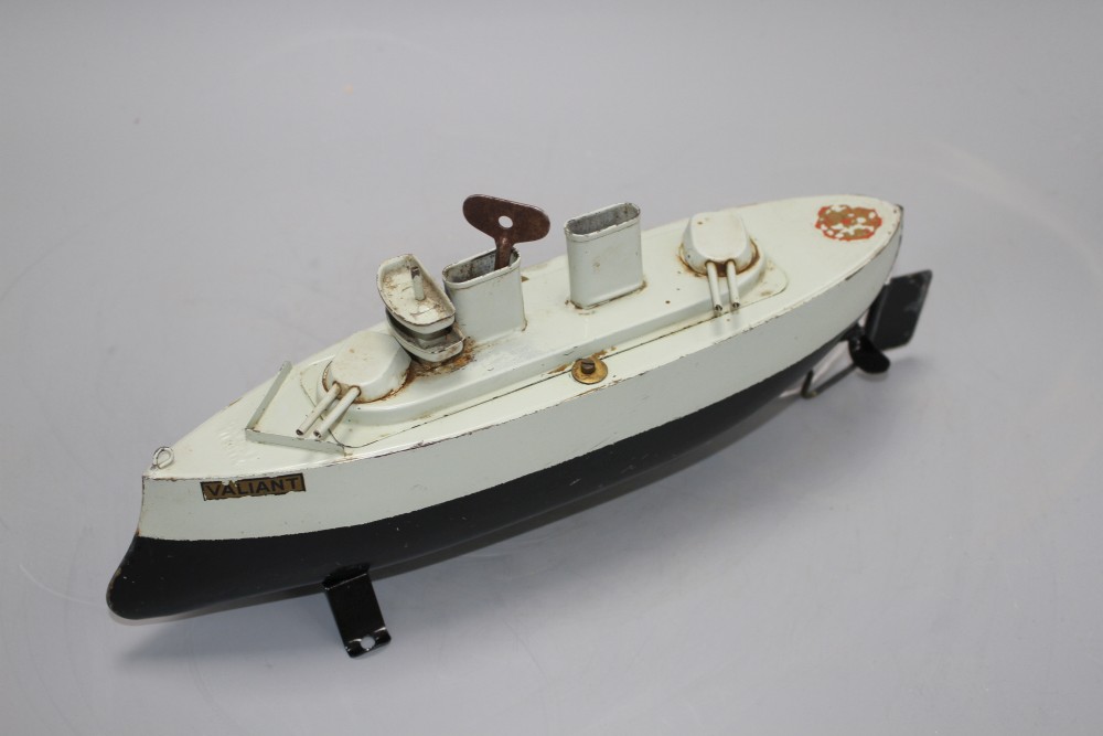 A Sutcliffe Valiant enamelled metal model battleship, clockwork with key and stand, unboxed